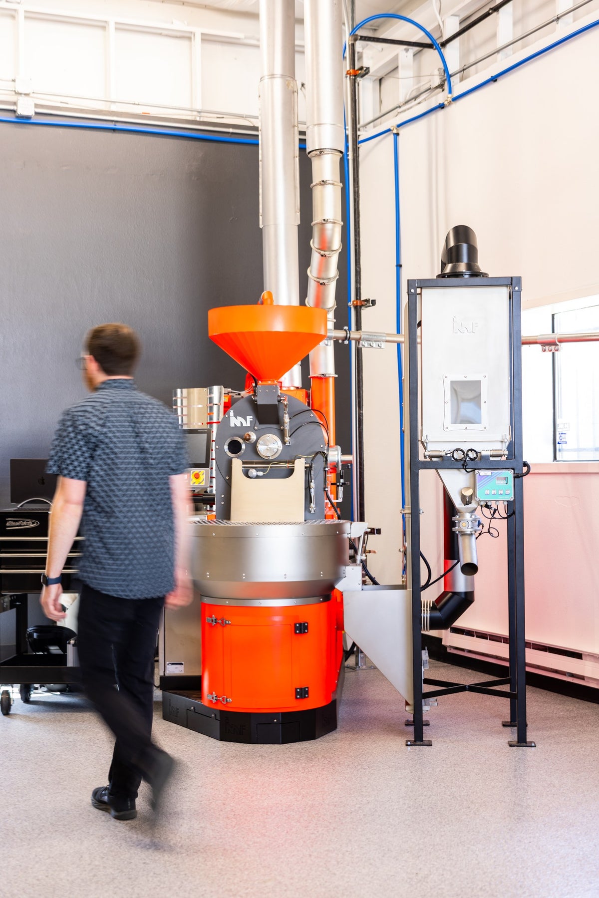 The Viafi roastery floor, with the roaster at the center and Jason walking past it